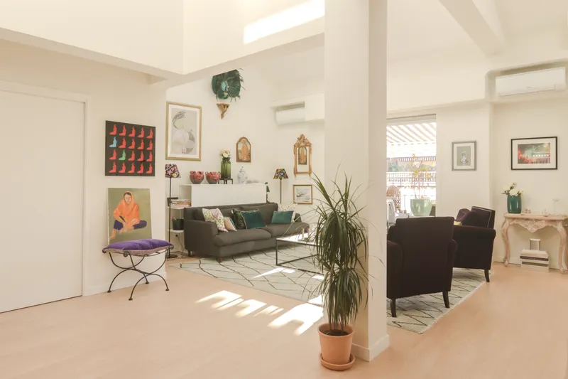 Salón luminoso con sofá, plantas y cuadros en la pared