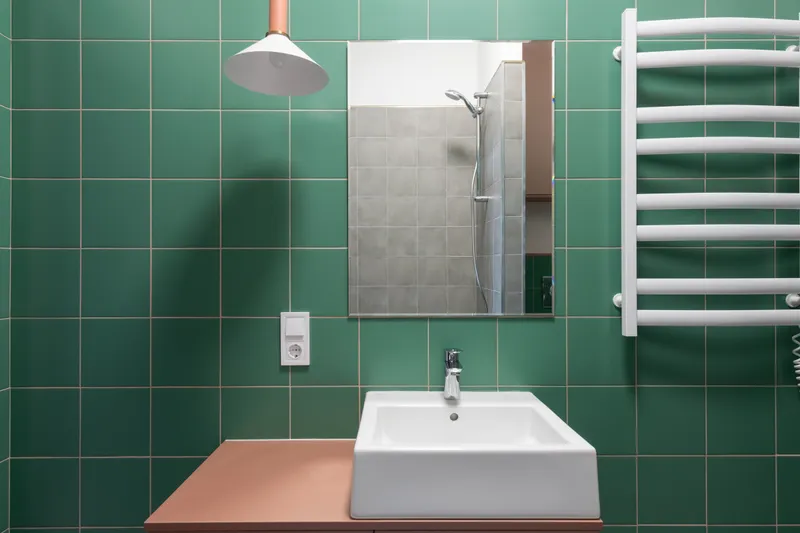 Baño alicatado en verde con lavabo blanco