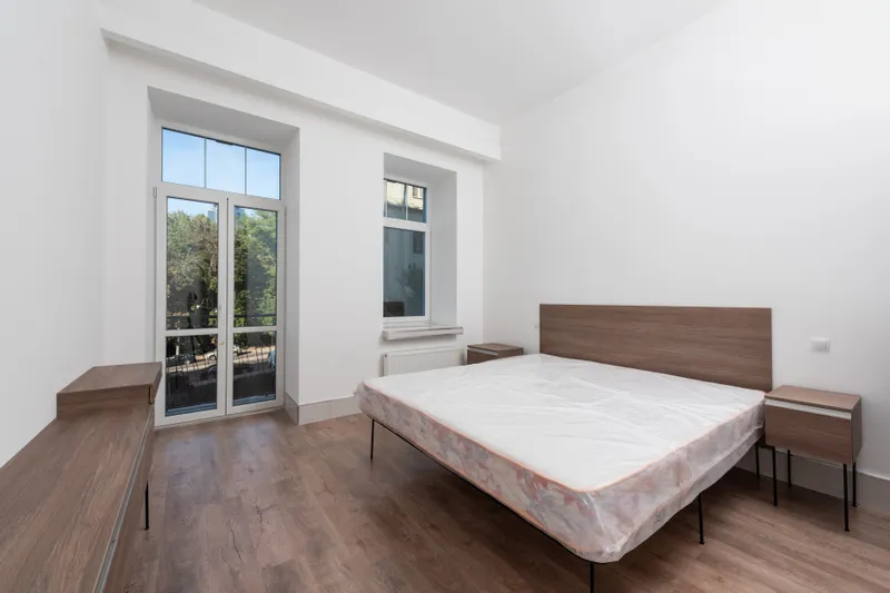 Dormitorio con ventana y suelo de madera
