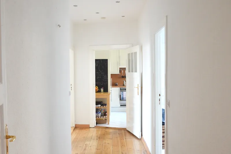 Pasillo con parquet y puerta abierta al fondo