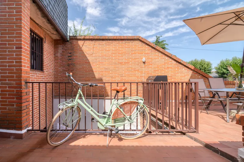 Terraza de ladrillo con bicicleta y sombrilla