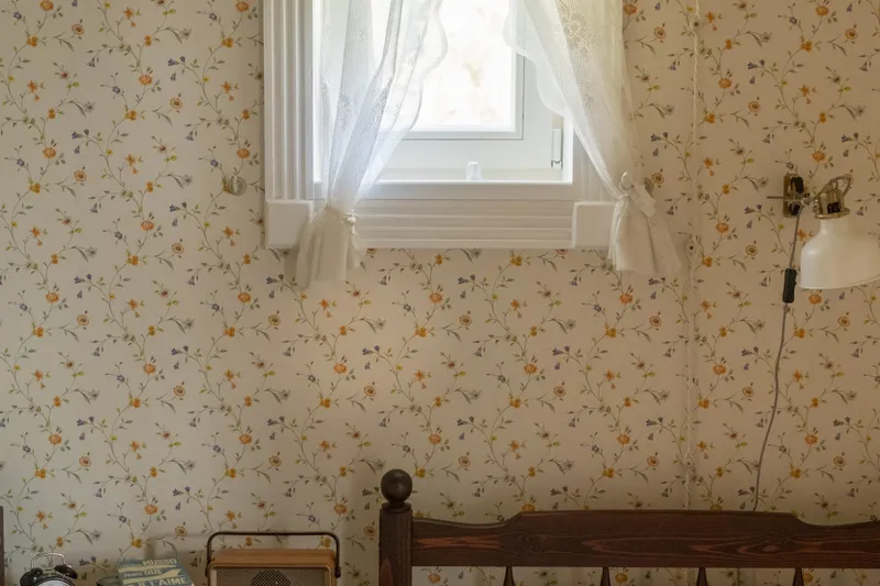 Dormitorio con papel pintado floral y ventana