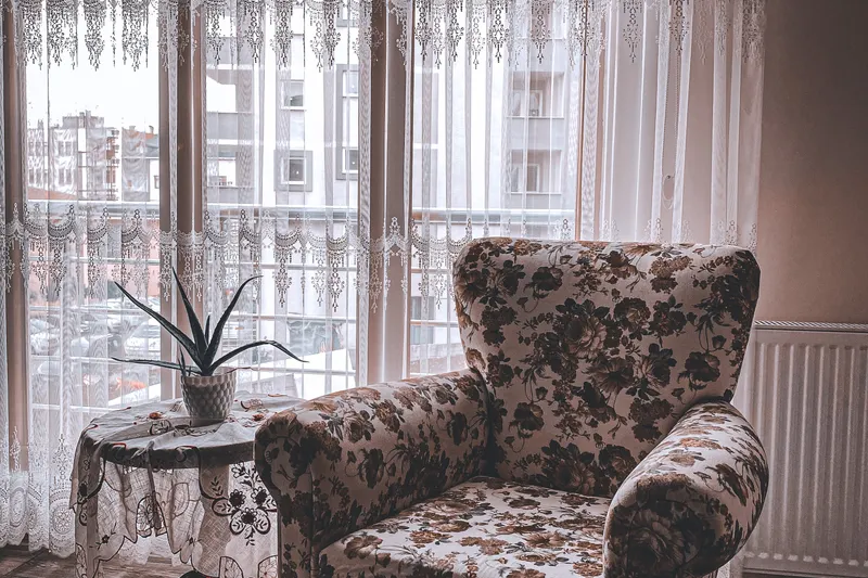 Salón con butaca de flores y visillos de encaje